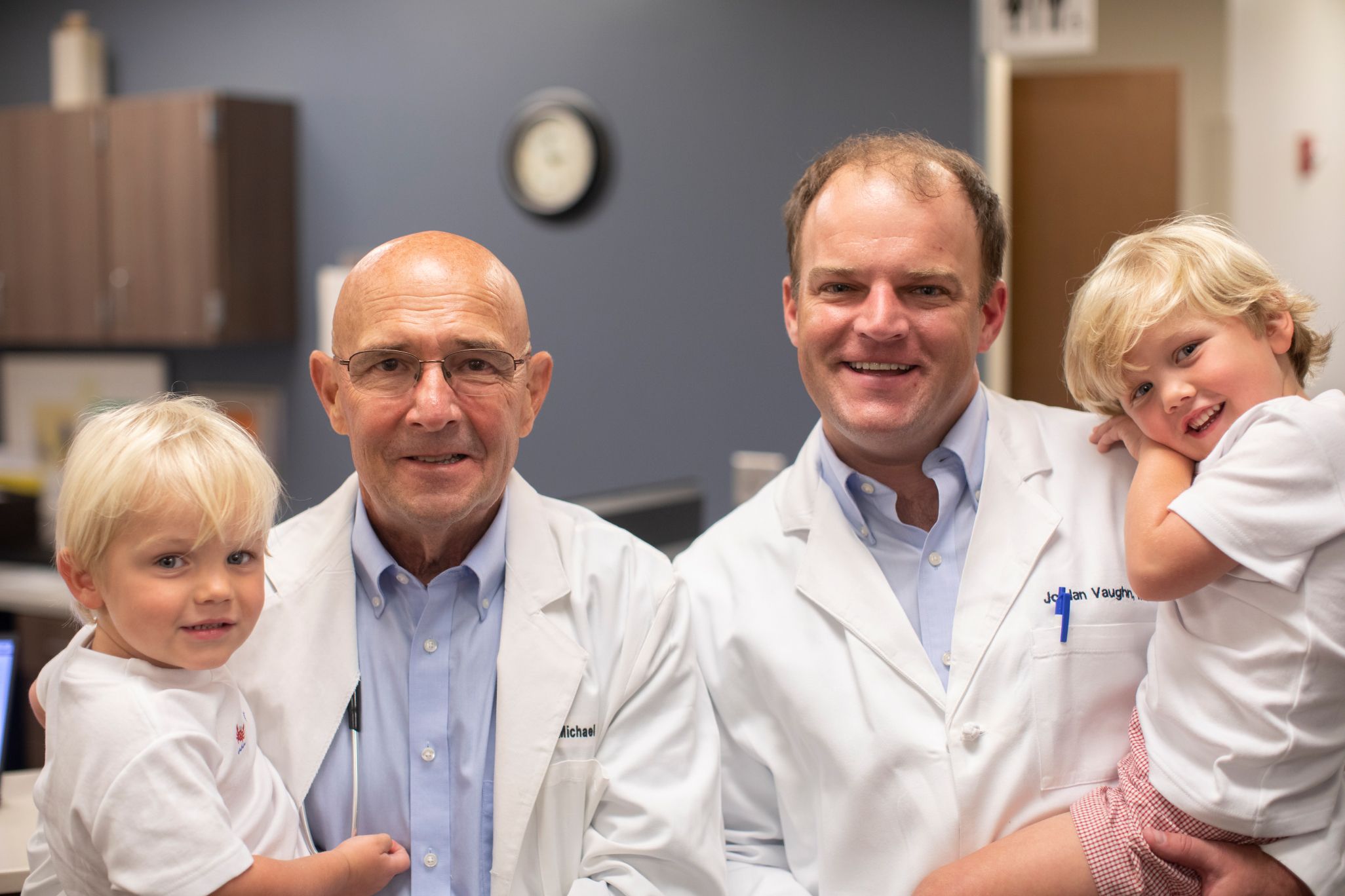 Michael Vaughn and Jordan Vaughn smiling at MedHelp Urgent Care holding two children