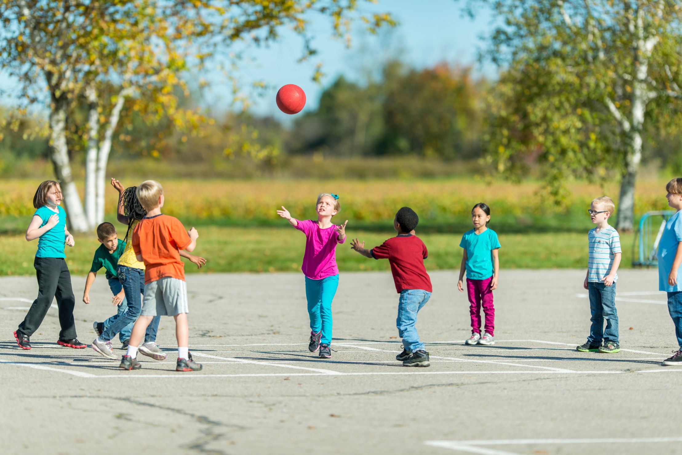 children playing with a ball outside on a sunny day back to school after covid-19