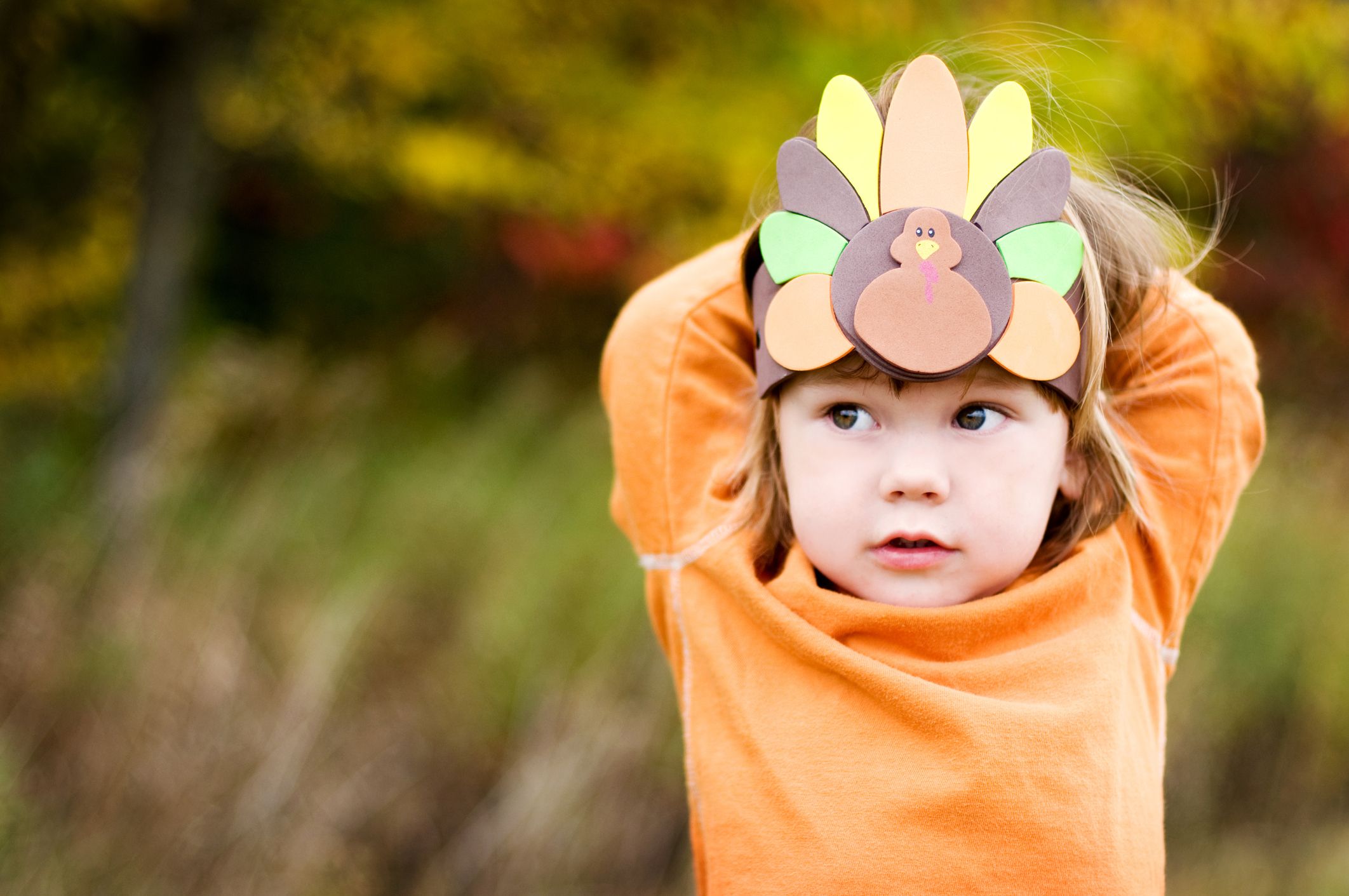 child in orange shirt wearing turkey hat craft at thanksgiving in covid