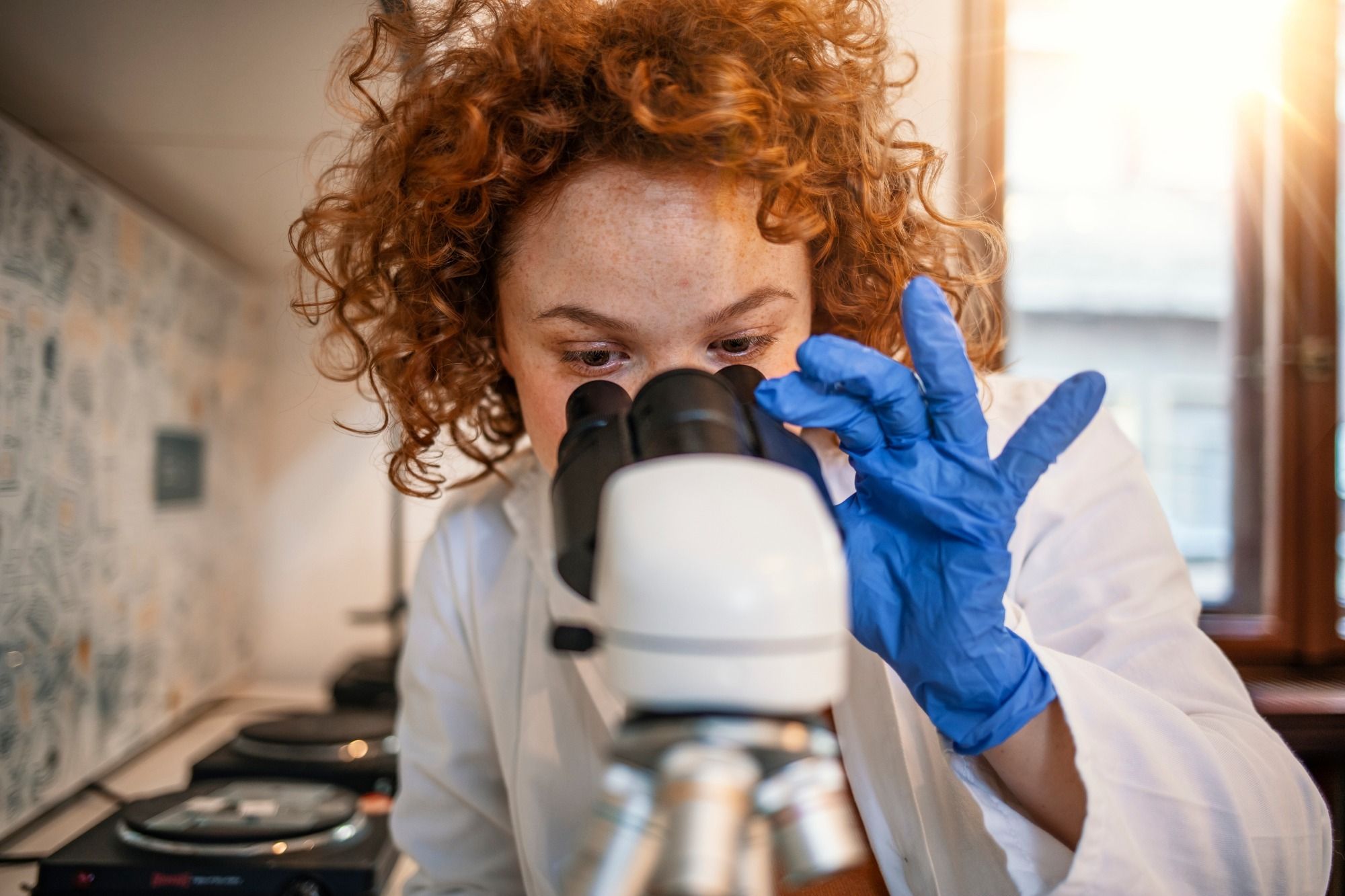 Woman in lab using a microscope to research coronavirus variants
