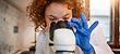 Woman in lab using a microscope to research coronavirus variants