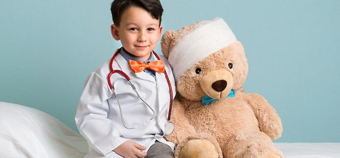 little boy wearing stethoscope and lab coat pretending to be a primary care doctor