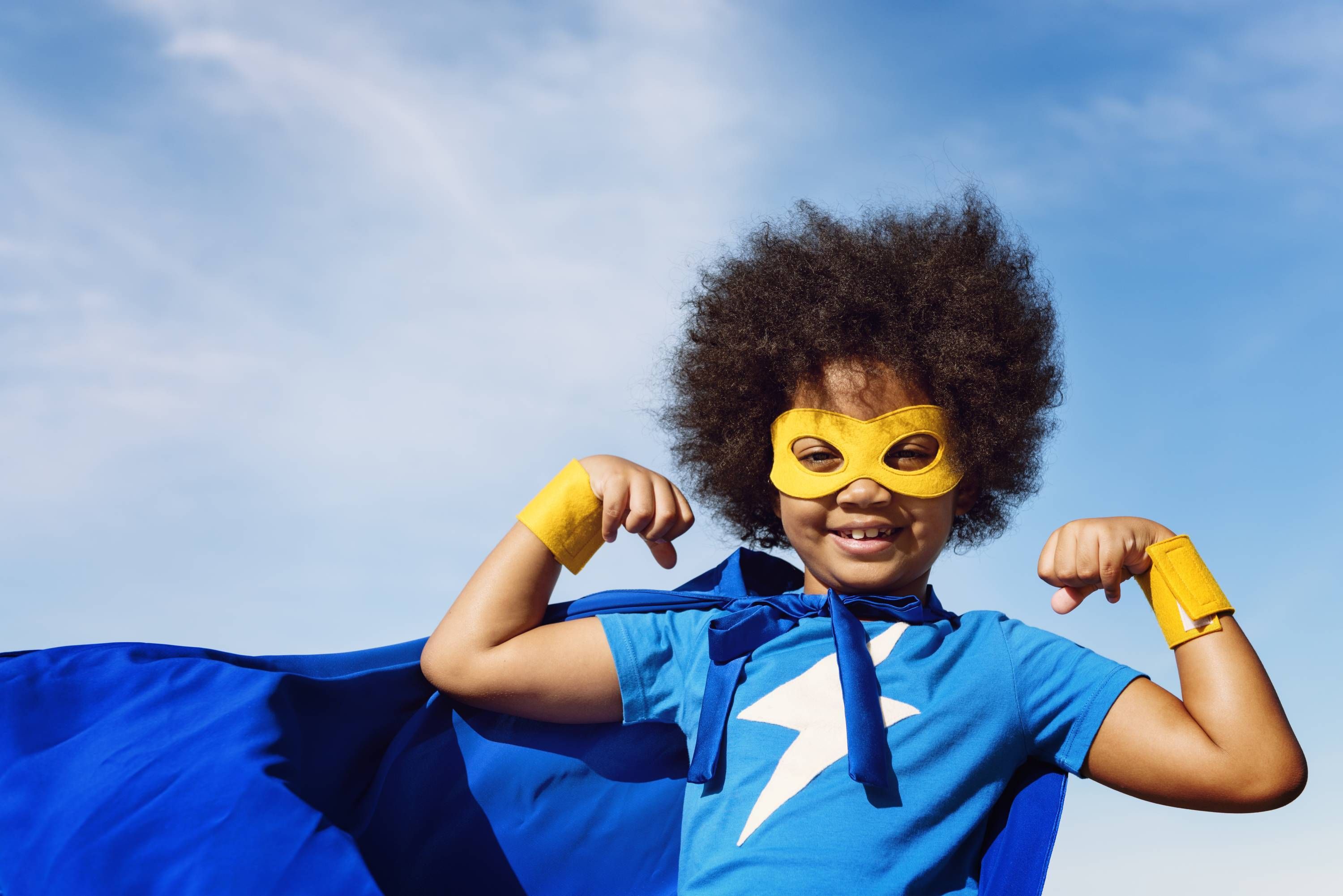 boy wearing superhero costume with cape and mask