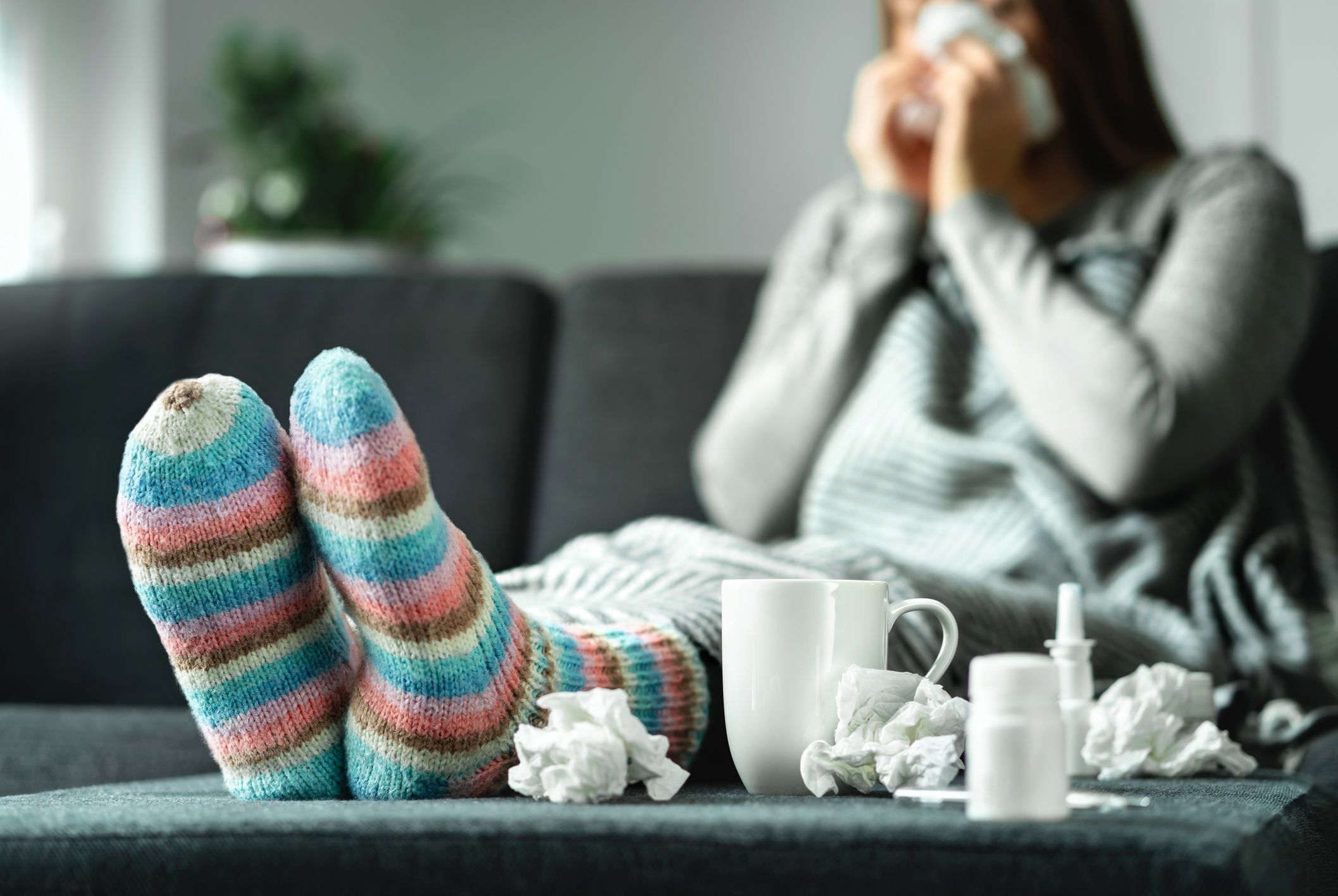 woman in comfy socks blowing her nose cold and flu