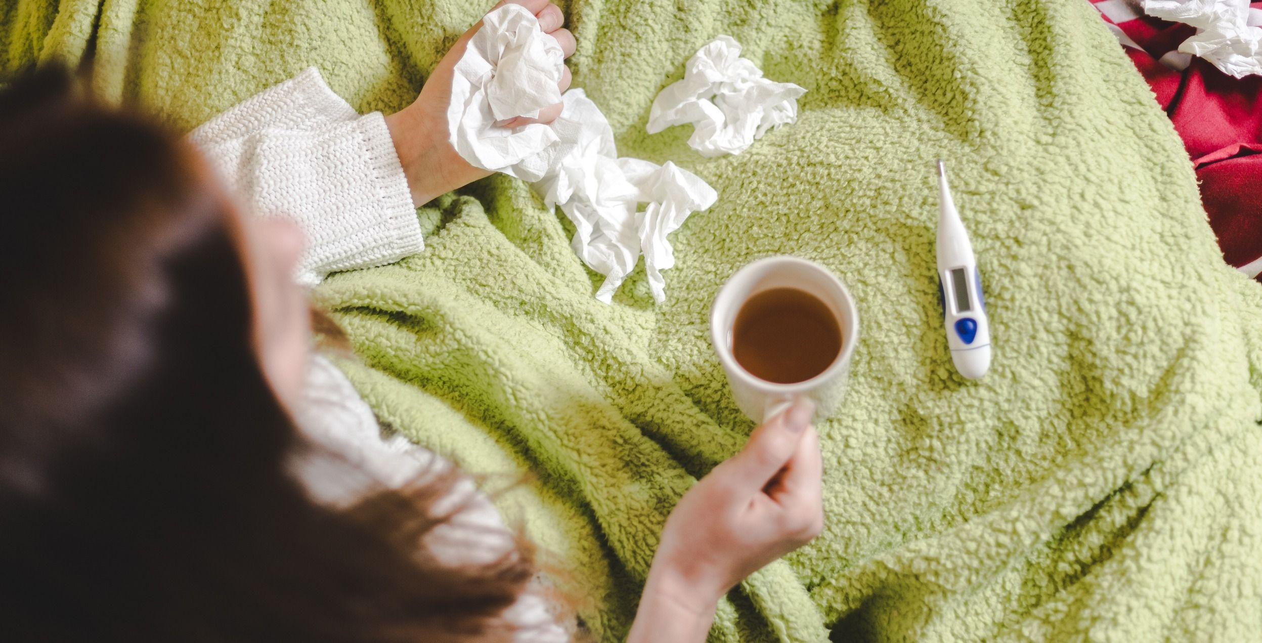 woman with respiratory illness in bed with tissues deciding to go to urgent care