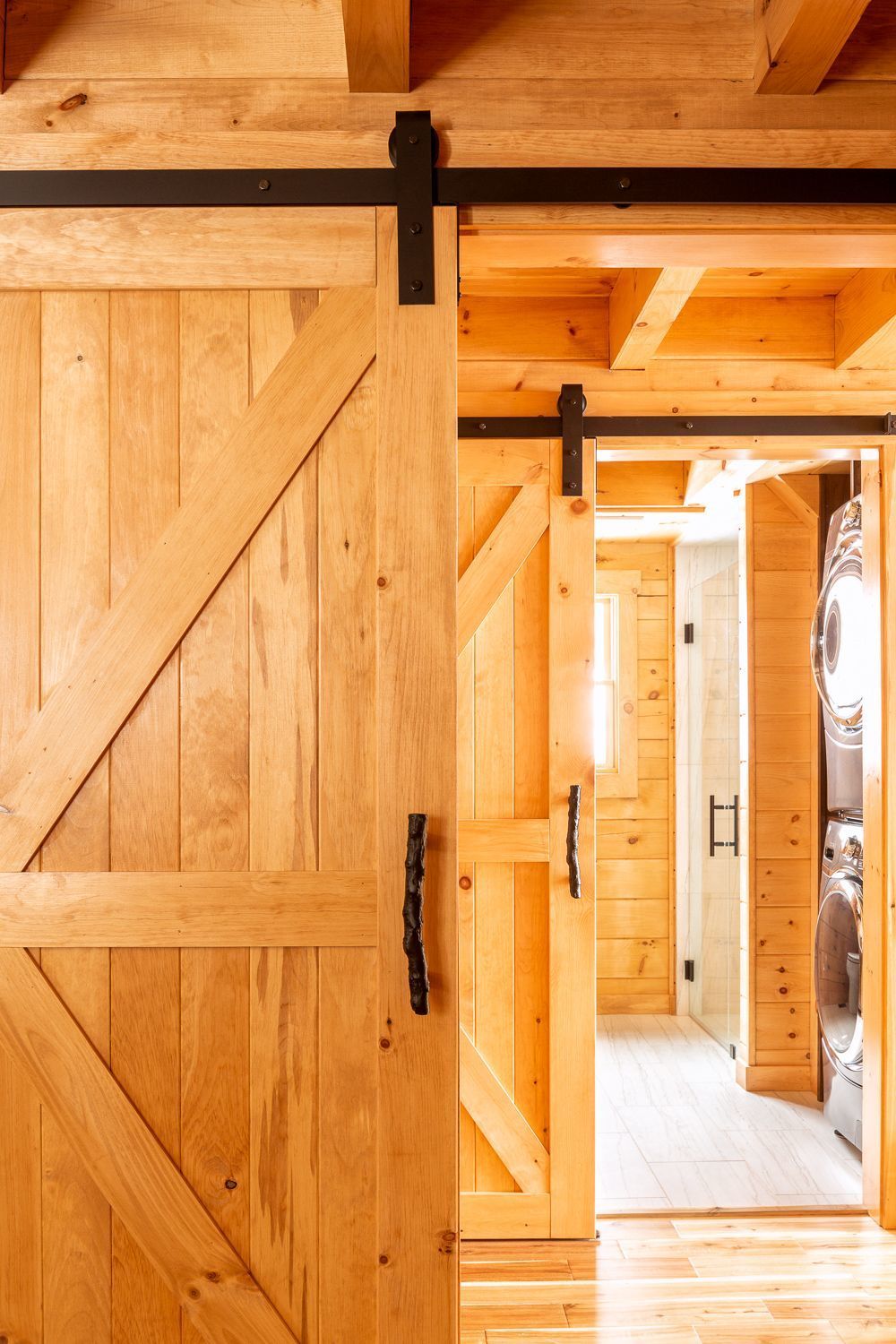 Series of custom barn doors with twig pole hardware from Emtek at Badger Camp